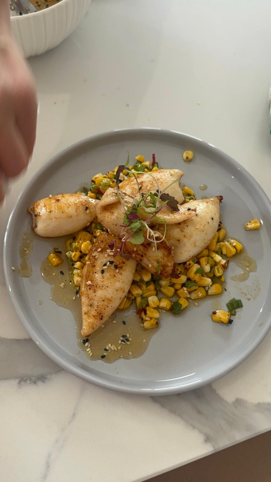 Seared seafood plated with charred corn and microgreens